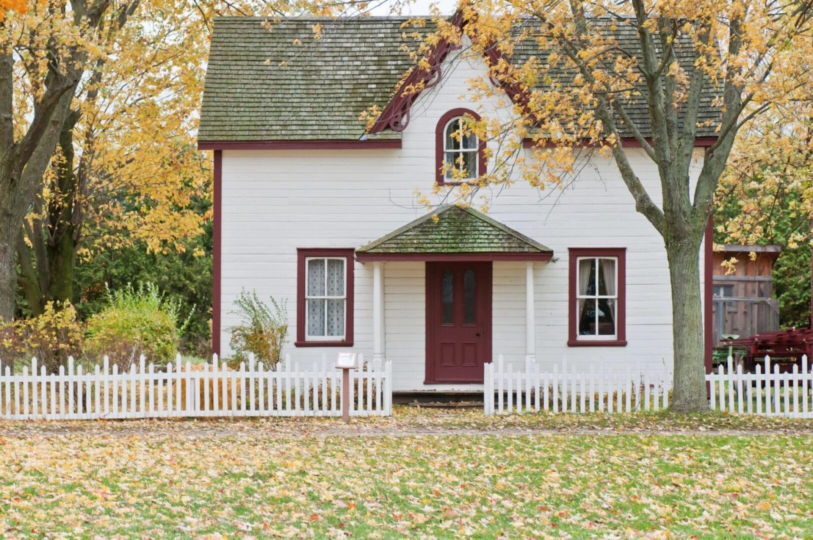 A Small White Color House in the Middle of Autumn Trees
